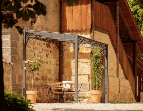 Pergola Elba in pulverbeschichtet anthrazit an einer Sandsteinwand angelehnt
