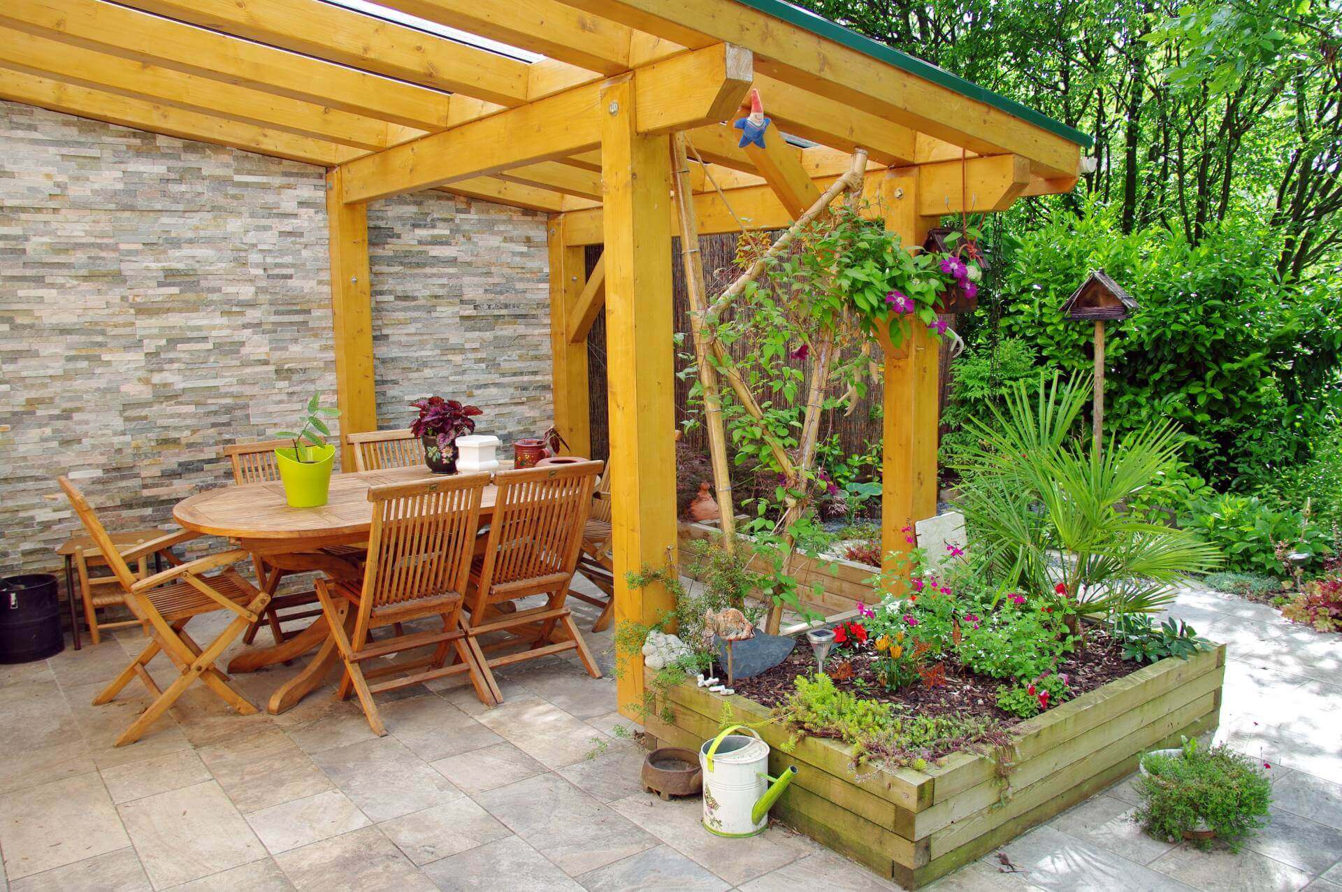 Selbst gebaute Pergola fertig dekoriert und bepflanzt mit Gartenmoebeln