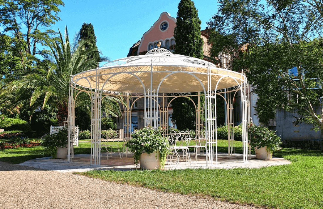 Pavillon Toskana in pulverbeschichteter Sonderfarbe weiss mit Sonnensegel und Messingkugel in einem Park